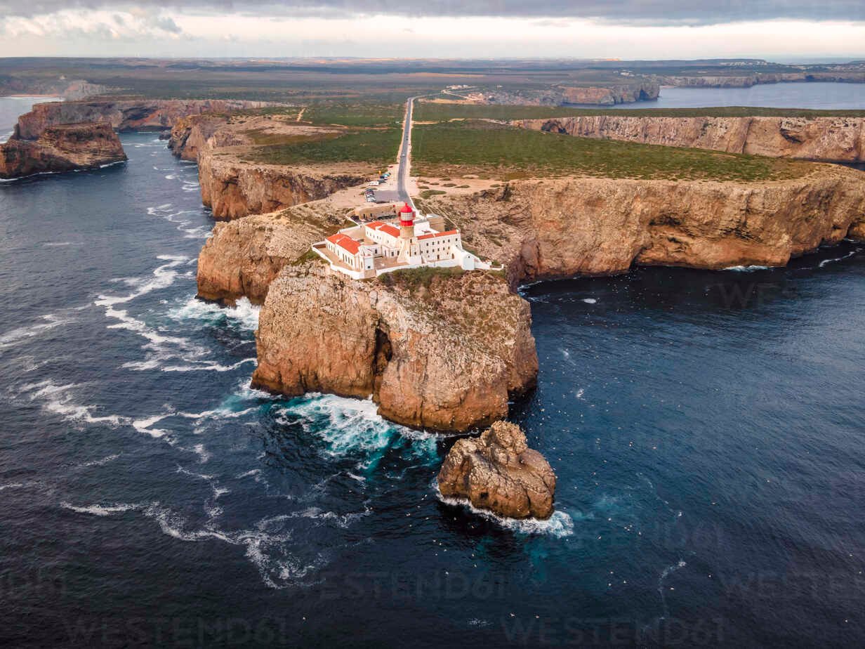 Aerial view of Farol do Cabo de Sao Vicente, a beautiful lighthouse on the cliff at sunset facing the ocean, Sagres, Algarve region, Portugal.